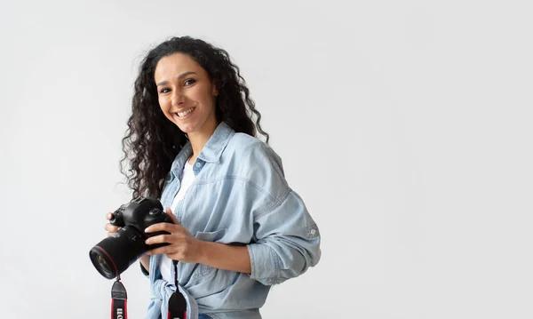 Mulher fotógrafa segurando foto câmera posando sobre parede branca — Fotografia de Stock