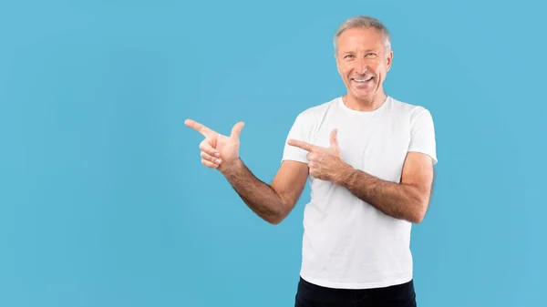 Excited mature man pointing aside at copy space — Stockfoto