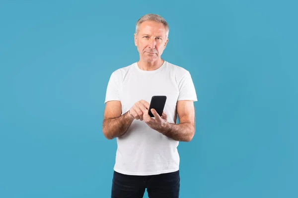 Pria dewasa menggunakan ponselnya di studio biru — Stok Foto