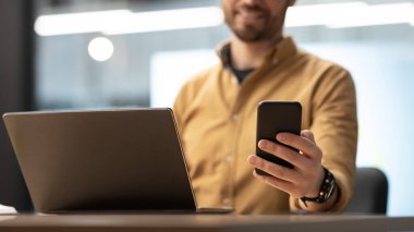 Akıllı Telefon Mesajı Kullanan İşadamı Ofiste Oturan Dizüstü Bilgisayarı Kullanıyor, Kesildi