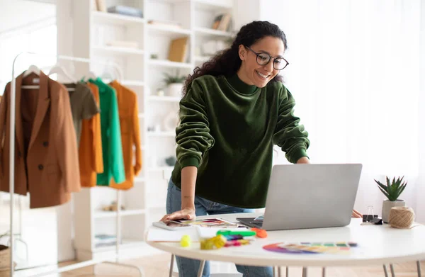 Mujer de diseño de ropa feliz usando el ordenador portátil de pie en la sala de exposición — Foto de Stock