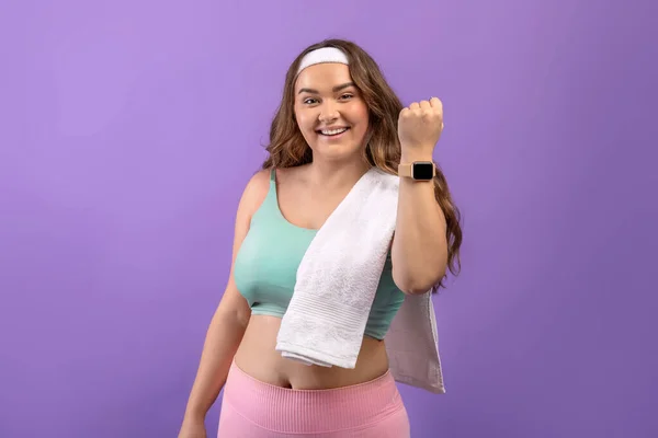 Glad young european plus size female in sportswear with towel show fit tracker after workout — 스톡 사진