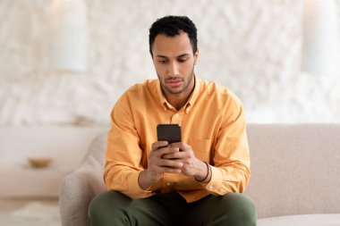 Genç adam evde akıllı telefon kullanıyor.