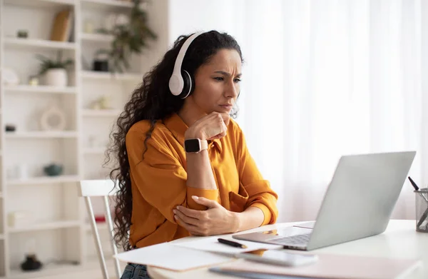 Concerned Middle Eastern Businesswoman Using Laptop Wearing Headphones In Office — стоковое фото