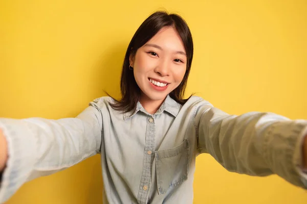 Rögzítő pillanatok. Boldog fiatal ázsiai hölgy csinál mobil szelfi felett sárga stúdió háttér — Stock Fotó