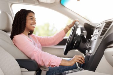 Gülümseyen siyah kadın şehirde yeni araba kullanıyor.