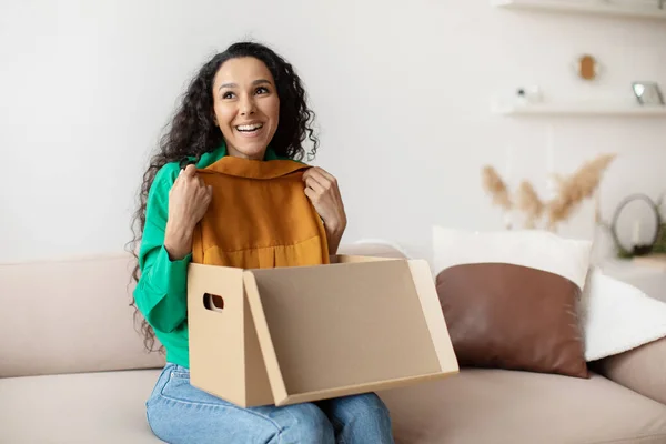 Vreugdevolle dame houdt nieuwe kleren uitpakken geleverd doos thuis — Stockfoto