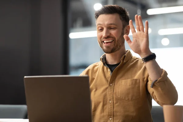 Hombre saludando Hola a la computadora portátil haciendo videollamada en la oficina — Foto de Stock