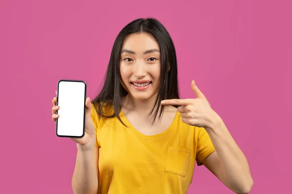 Podívej se na tohle. vzrušená korejská dáma ukazuje na smartphone s prázdnou obrazovkou na fialovém pozadí, maketa — Stock fotografie