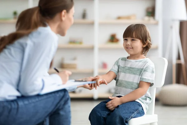 Pierwsze spotkanie z pacjentem. Przyjazna profesjonalistka psycholog dziecięcy powitanie cute little boy, dotykając jego rękę — Zdjęcie stockowe