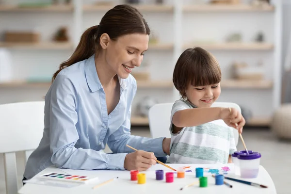 Ευτυχισμένο μικρό αγόρι ζωγραφίζει με δάσκαλο στη σχολή καλών τεχνών, αναπτύσσοντας δεξιότητες δημιουργικότητας με χρώματα, κενό χώρο — Φωτογραφία Αρχείου