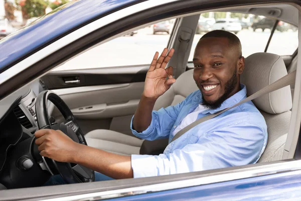 Boldog fekete férfi ül az autóban, és jó gesztust mutat. — Stock Fotó
