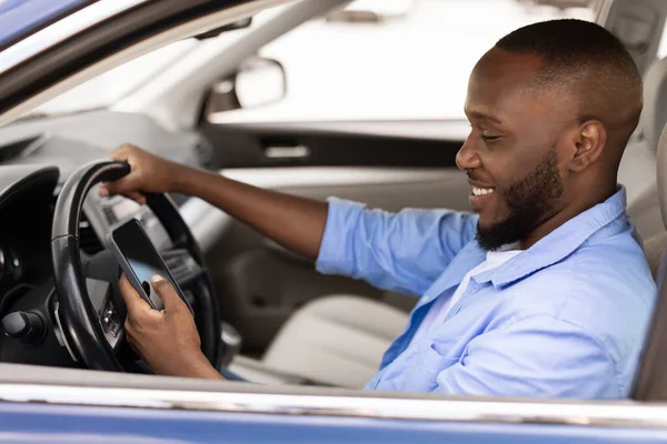 Boldog fekete férfi használ bemutató okostelefon vezetés autó — Stock Fotó