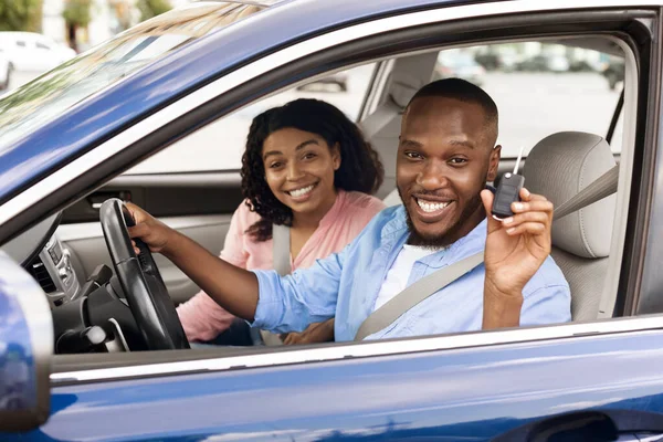 Feliz negro pareja sentado en coche mostrando llaves —  Fotos de Stock