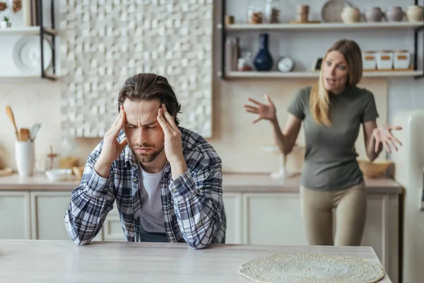 Despaired offended millennial european man with stubble hold his head with hands, ignoring screaming lady after scandal — Stock Photo, Image