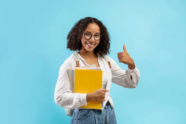 Vrolijke zwarte vrouwelijke student met rugzak en notebooks tonen duim omhoog, aanbevelen van moderne academische opleiding — Stockfoto