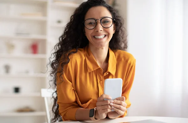 Alegre mujer de Oriente Medio usando teléfono móvil posando sentado en el interior — Foto de Stock