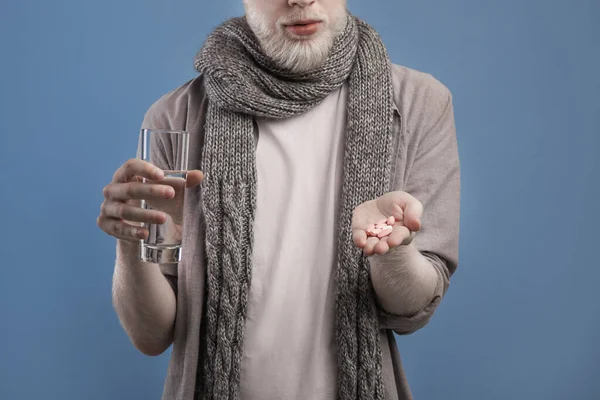 Gewassen beeld van de mens het nemen van pillen, het houden van glas zoet water op blauwe studio achtergrond, bijgesneden, close-up — Stockfoto