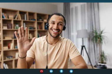 Videocall screenshot of cheerful arab man in headset having web conference, waving hand at camera and smiling clipart