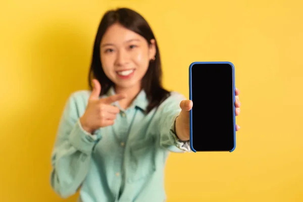Positive Millennial Asiatin zeigt auf Smartphone mit leerem Bildschirm, Werbung für neue App oder Website, Attrappe — Stockfoto