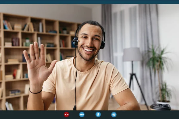 Videocall screenshot vidám arab férfi headset amelynek web konferencia, integető kéz a kamera és mosolygós — Stock Fotó