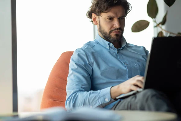 Επιχειρηματίας που χρησιμοποιεί φορητό υπολογιστή κάθεται σε σακούλα φασολιών στο γραφείο — Φωτογραφία Αρχείου