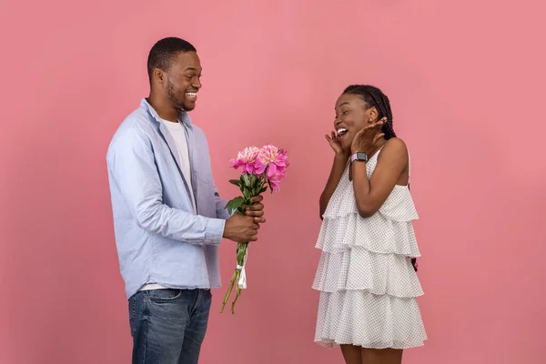 Szczęśliwy czarny mężczyzna co niespodzianka dla kobieta dając kwiaty — Zdjęcie stockowe