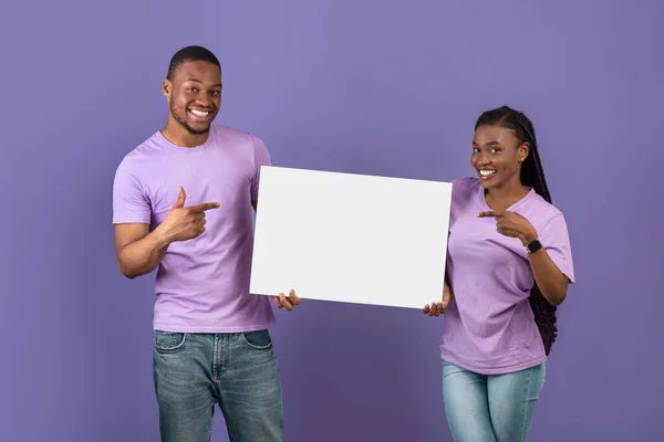 Μαύρο ζευγάρι κρατώντας και δείχνοντας λευκό λευκό διαφημιστικό πλακάτ — Φωτογραφία Αρχείου