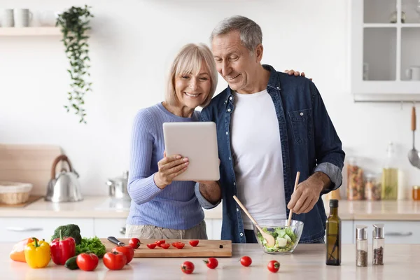 Seniorenpaar liest Rezept auf digitalem Tablet in Küche — Stockfoto