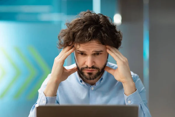 Triste uomo d'affari afferrare la testa con il computer portatile — Foto Stock