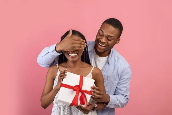 Happy black man making surprise for his lady covering eyes — стоковое фото