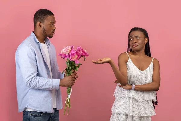 Black man making surprise for bored woman giving flowers — Stock Photo, Image