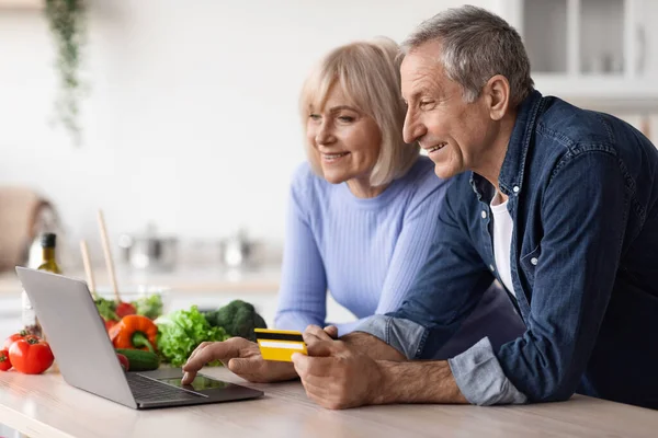 Pozitivní starší pár dělat online objednávky, pomocí notebok — Stock fotografie