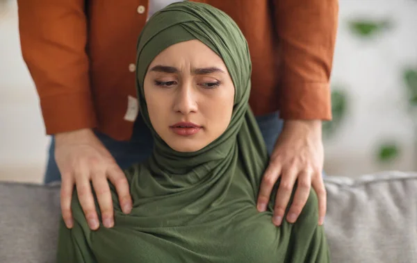 Unerkennbarer muslimischer Ehemann berührt unglückliche Ehefrauen im Haus an den Schultern — Stockfoto
