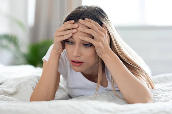 Depressed young woman laying in bed alone at home — Stock Photo, Image