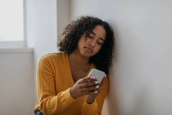 Unhappy young black woman reading terrible news on cellphone, overusing internet at home — Foto Stock