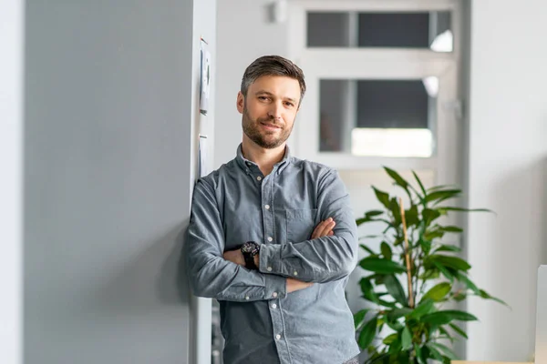 Retrato de empresário maduro bem sucedido na camisa de pé no salão de escritório moderno, posando com as mãos cruzadas, espaço livre — Fotografia de Stock