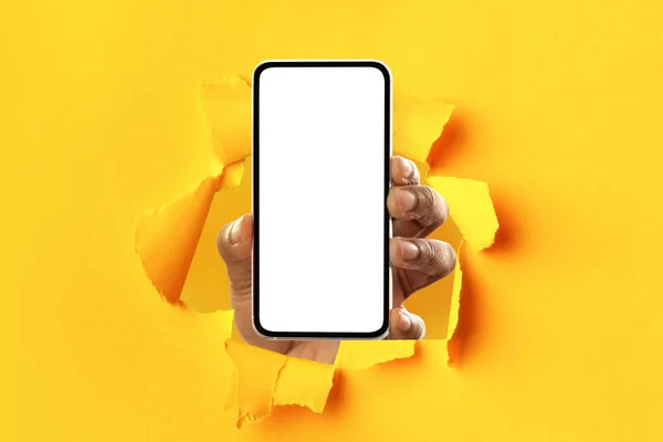 Schwarze Person zeigt weißen leeren Smartphone-Bildschirm, der Papier durchbricht — Stockfoto