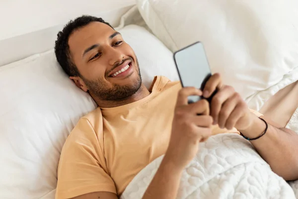 Above View Of Arabic Man Using Phone Texting In Bedroom — стоковое фото