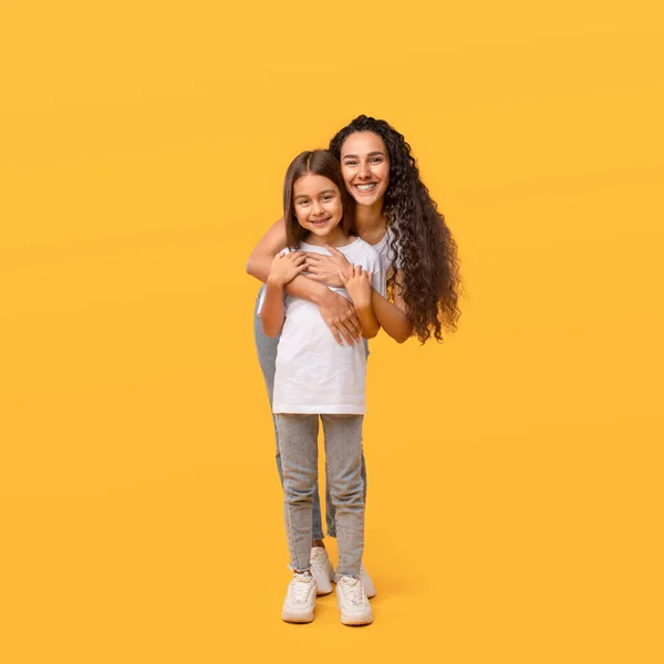 Happy Arabic Mother Hugging Little Daughter Standing Over Yellow Background — Stockfoto