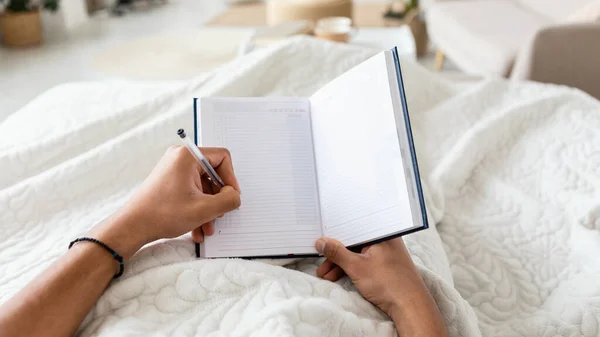 Male Holding Planner In Hands Taking Notes In Bedroom, POV — Stock Photo, Image