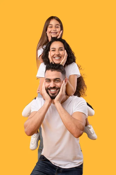 Homem árabe feliz segurando esposa e filha em ombros, Estúdio — Fotografia de Stock
