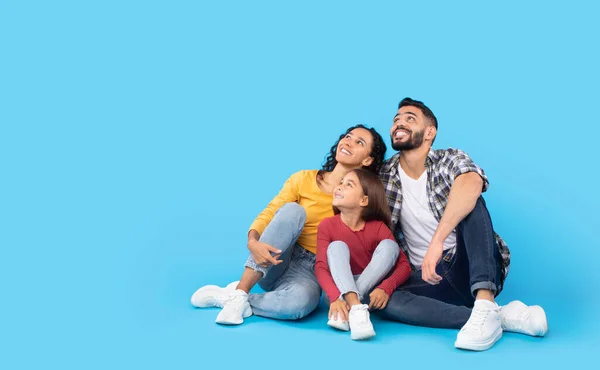 Família do Oriente Médio feliz sentada olhando para cima sobre fundo azul — Fotografia de Stock