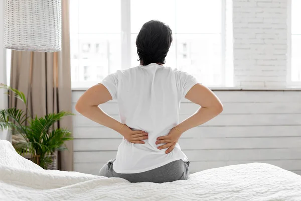 Man suffering from back pain at home in bedroom — Stock Photo, Image