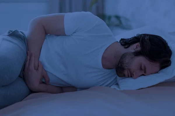 Sick man suffering from stomach cramps at night — Foto Stock