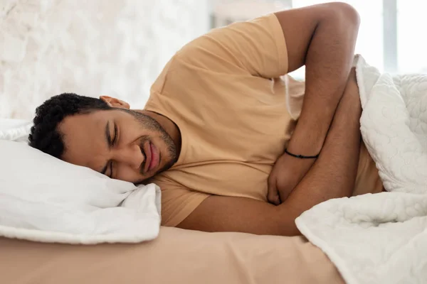 Arabic Guy Suffering From Abdominal Pain Touching Tummy In Bedroom — Fotografia de Stock