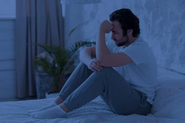 Sleepless millennial man feeling down at night, bedroom interior — Fotografia de Stock