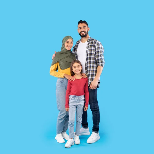 青い背景の上に立つ笑顔を抱きしめる幸せなムスリム家族 — ストック写真