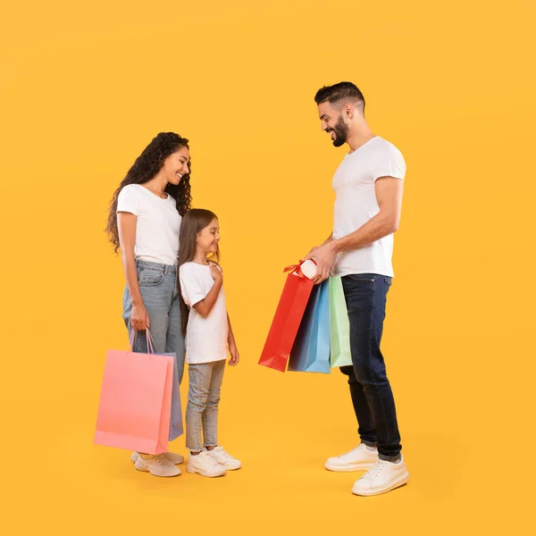 Ebeveynler Kızlarına Hediye Veriyor ve Alışveriş Torbaları Veriyor, Sarı Arka plan — Stok fotoğraf
