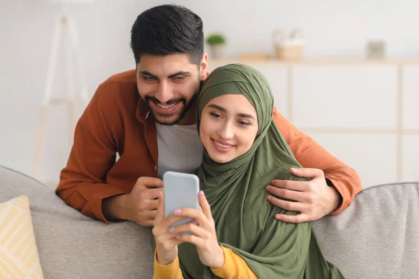 Middle Eastern Spouses Using Mobile Phone Texting Sitting At Home — Stock Photo, Image